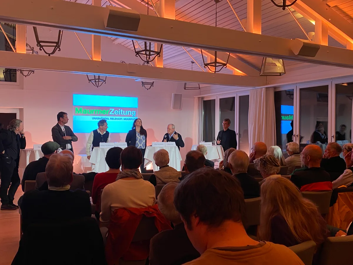 Menschen stehen hinter Stehpulten und führen eine Podiumsdiskussion.